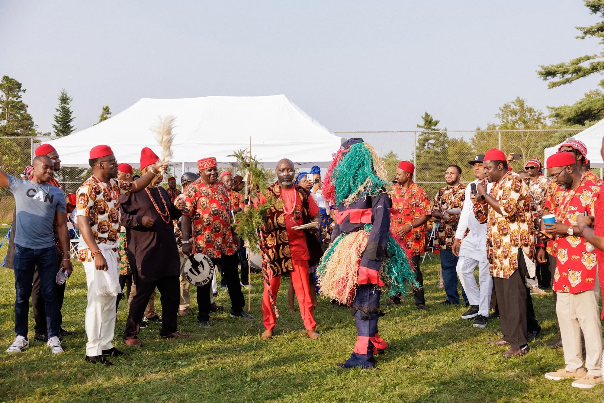 A masquerade dances through a crowd in red caps